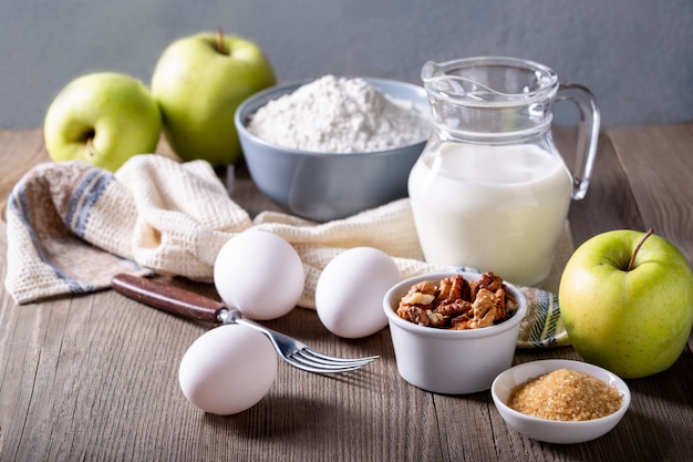 Leche, harina, huevos y manzanas verdes en una mesa de madera. Ingredientes para Apple Charlotte