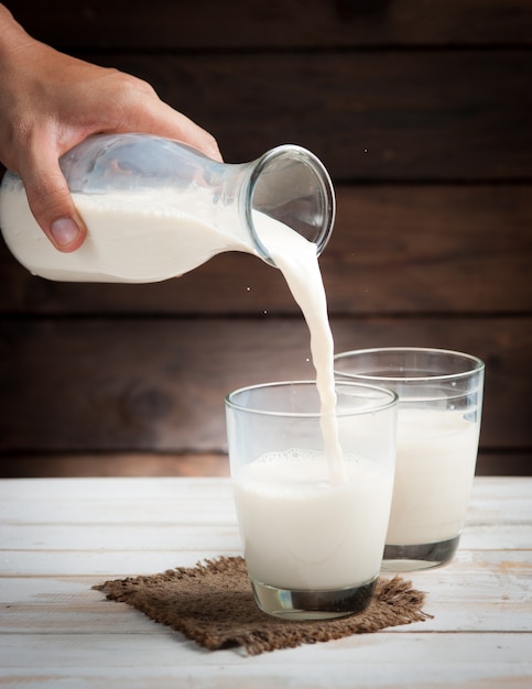 Leche de una jarra que se vierte en el vaso