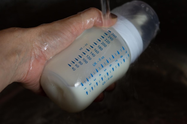 Leche materna en el biberón que se descongela con agua corriente