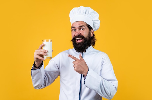 Leche natural en la mano de un lechero panadero experto que usa utensilios de cocina para cocinar chef con sombrero preparar comida hombre guapo con barba y bigote cocinando comida restaurante profesional cocinero horneado