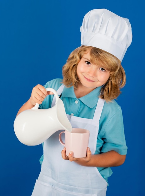 Foto leche para niños niño chef cocinero prepara comida en fondo de estudio azul aislado niños cocinando adolescente