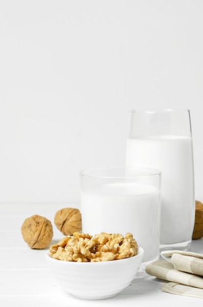 Foto leche de nueces y nueces sobre un fondo de madera blanca. productos que contienen proteínas vegetales, vitaminas y aminoácidos útiles. para una dieta sana y vegetariana. copie el espacio.