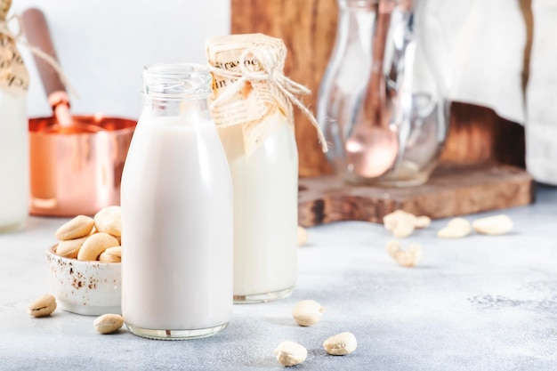 Leche de nuez de anacardo en botellas sobre fondo blanco Leche vegana alternativa no láctea Concepto de comida y bebida vegetariana y dietética saludable