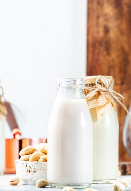 Leche de nuez de anacardo vegana en botellas primer plano fondo de mesa blanco Leche alternativa no láctea Concepto de comida y bebida vegetariana saludable Espacio de copia