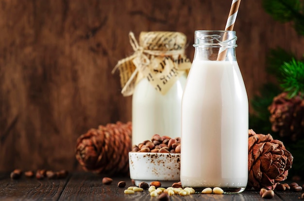 Leche de nuez de cedro vegano en botellas primer plano fondo de mesa de madera Leche alternativa no láctea Concepto de comida y bebida vegetariana saludable Espacio de copia