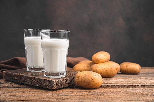 Leche de patata vegana en dos vasos y patatas sobre fondo marrón Espacios de copia de vista lateral