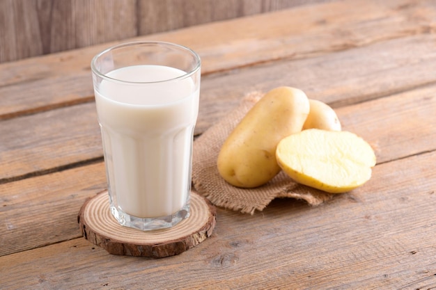 Leche de patata vegana y patata sobre fondo de madera marrón cerca de leche alternativa a base de plantas