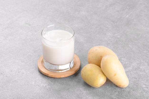 Leche de patata vegana y patata sobre fondo de mesa de piedra gris sustituto de leche alternativo a base de plantas