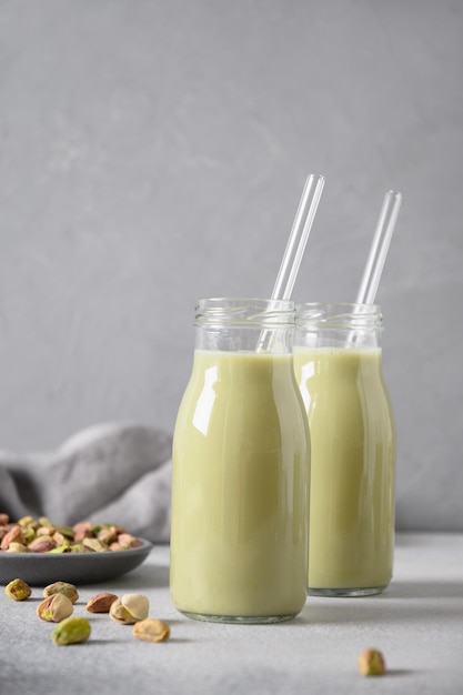 Leche de pistacho en botellas sobre fondo gris Sin lactosa Leche a base de plantas de nuez vegana Formato vertical