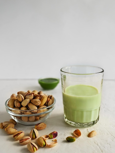 Foto leche de pistacho en el vaso y pasta de pistacho en el fondo blanco esta leche es una gran fuente de fitoesteroles antioxidantes y grasas saludables para el corazón