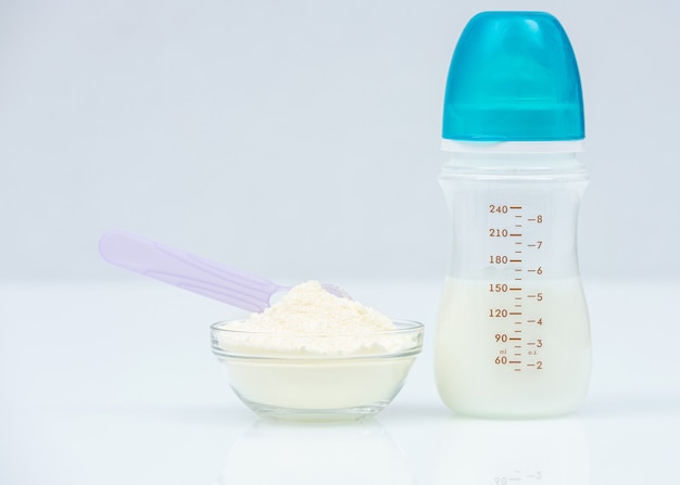 Leche en polvo, fórmula para bebés con fórmula infantil de cuchara en un tazón y biberón para alimentar al bebé