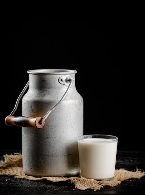 Leche rústica en una lata y un vaso sobre la mesa