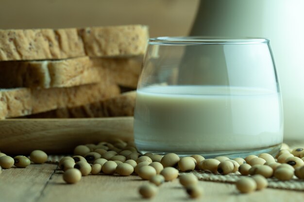 Leche de soja en jarra de vidrio y pan integral en disco de madera