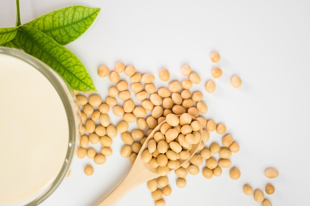 Leche de soja y soja en el fondo blanco de la tabla, concepto saludable. Beneficios de la soya.