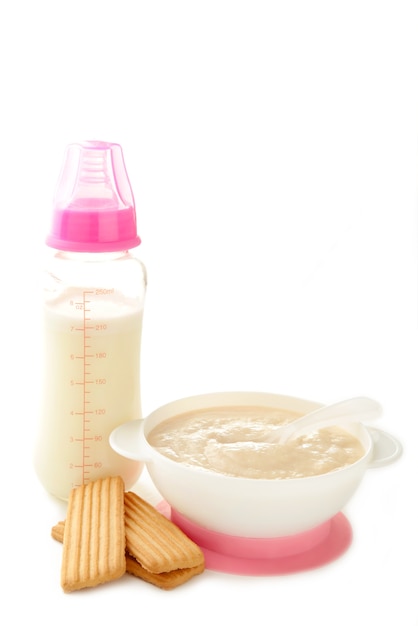 Leche y tazón con papilla para bebé aislado en blanco