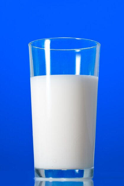 Leche en vaso aislado en azul