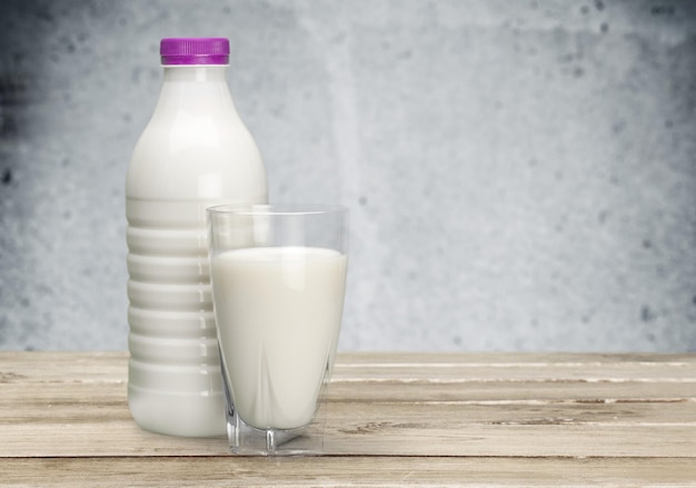 Leche en vaso y botella en una mesa de madera