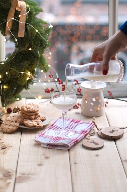 leche en un vaso, galletas en un plato y una corona de árbol de navidad