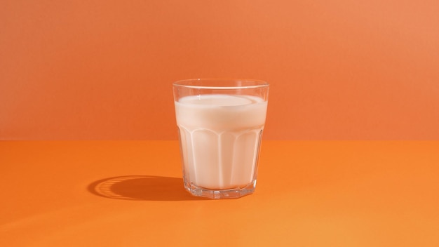 Leche en vaso sobre fondo naranja