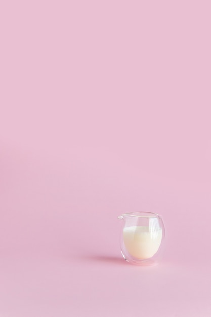 Foto leche en un vaso sobre un fondo rosa. foto vertical