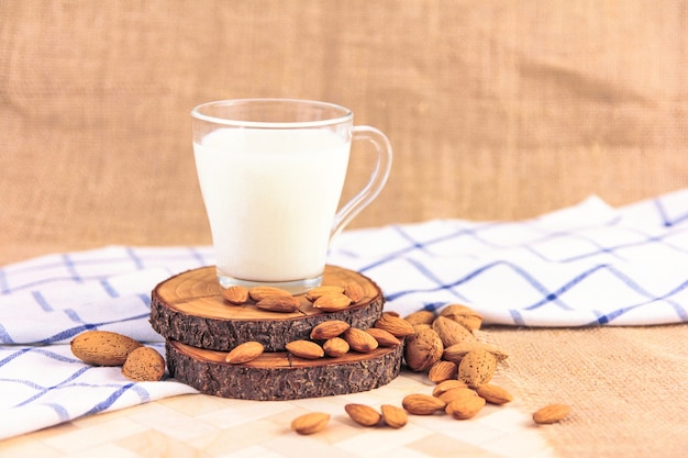 Leche en vaso sobre las rodajas de madera con semillas de almendra