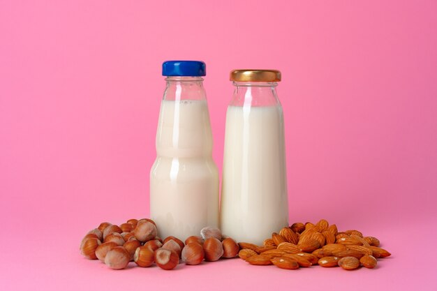 Leche vegana no láctea hecha de nueces en cristalería contra rosa cerrar