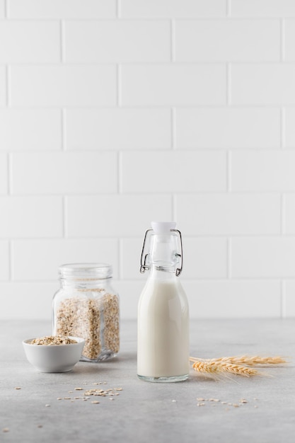 Leche vegetal alternativa de copos de avena en una botella sobre un fondo claro Leche vegetariana