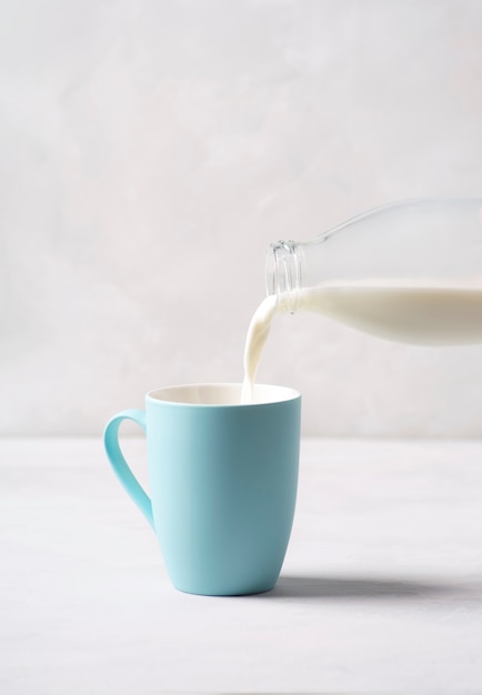 La leche se vierte en una taza azul de una botella de vidrio.