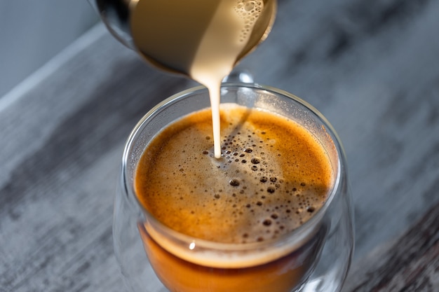 La leche se vierte en una taza de café. Café vigorizante matutino