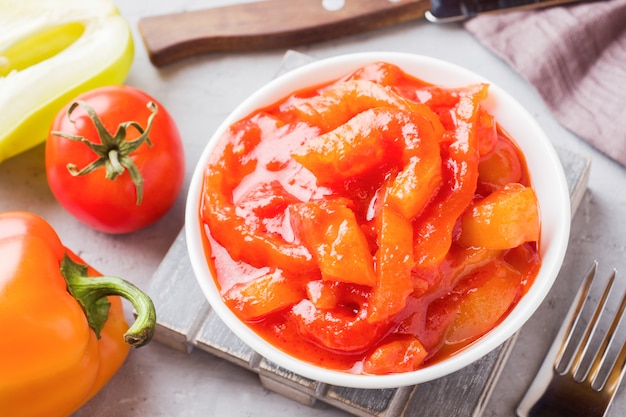 Lecho enlatado de los pimientos y tomates, cosechando para el invierno.