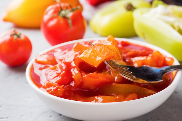 Lecho enlatado de los pimientos y tomates, cosechando para el invierno.