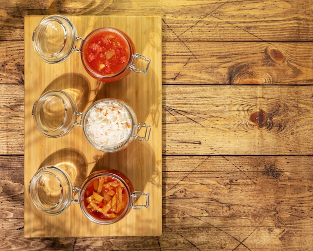 Lecho sauerkraut ajvar en frascos de vidrio sobre un fondo de madera con espacio de copia