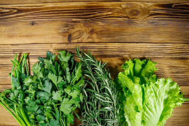 Lechuga de perejil fresco deja cebolla verde y hierbas de romero en la mesa de madera Vista superior