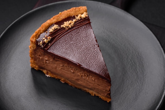Lecker frischer süßer Schokoladenkuchen mit in Scheiben geschnittenen Nüssen auf einem dunklen Betongrund
