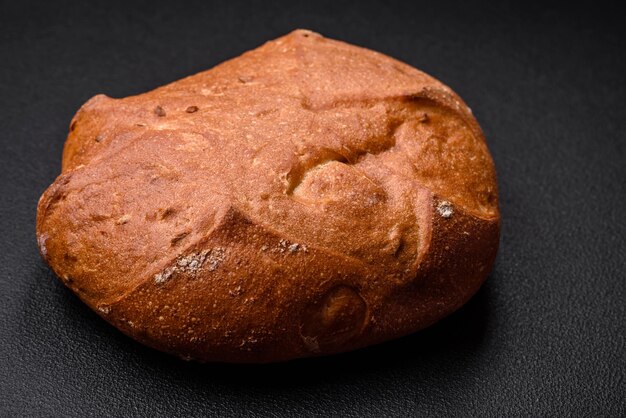 Lecker frisches knuspriges braunes Brot mit Samen und Körnern auf einem dunklen Betongrund