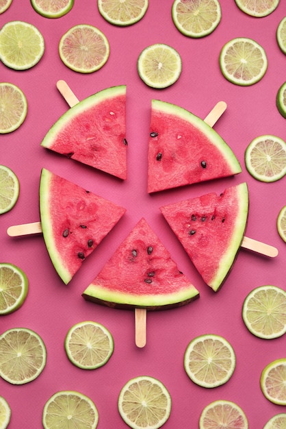 Lecker geschnittene Wassermelone und Limetten auf rotem Hintergrund flach gelegt