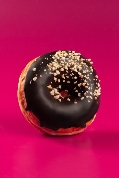 Lecker glasierter runder Donut auf einem hellen rosa Hintergrund