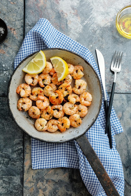 Foto leckere, appetitlich gebratene garnelen auf pfanne auf dunklem steinhintergrund draufsicht