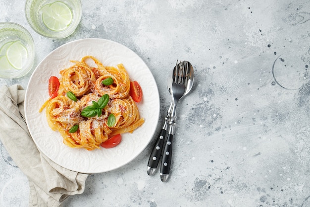 Leckere appetitliche klassische italienische Tagliatelle-Nudeln mit Tomatensauce, Käseparmesan und Basilikum auf dem Teller auf dem Leuchttisch. Ansicht von oben, horizontal. Draufsicht mit Kopienraum.