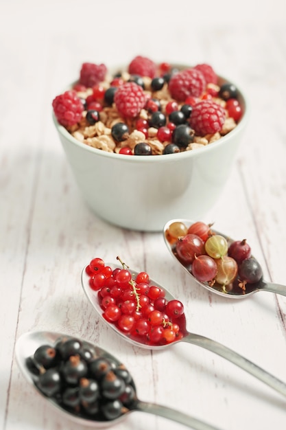 Leckere Beeren in einer weißen Tasse und Löffeln