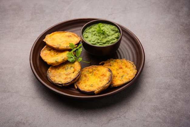 Leckere Brinjal Pakora oder knusprige Auberginenkrapfen, indischer Tea Time Snack serviert mit grünem Chutney