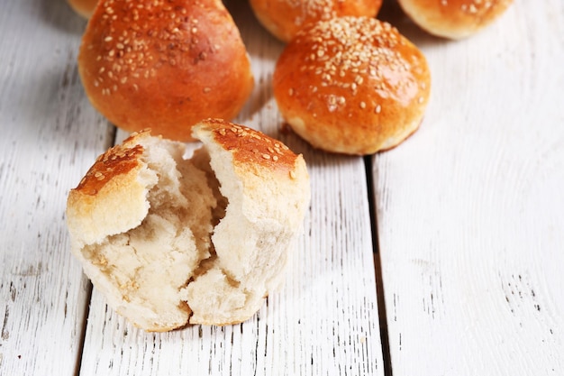 Leckere Brötchen mit Sesam auf farbigem Holzhintergrund