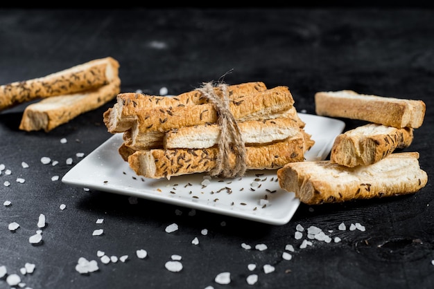 Leckere Brotstangen mit Kreuzkümmel auf schwarzem Hintergrund