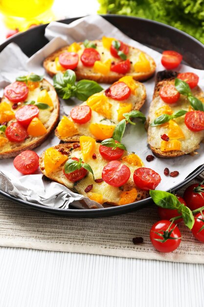 Leckere Bruschetta mit Tomaten in der Pfanne auf dem Tisch