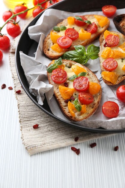 Leckere Bruschetta mit Tomaten in der Pfanne auf dem Tisch