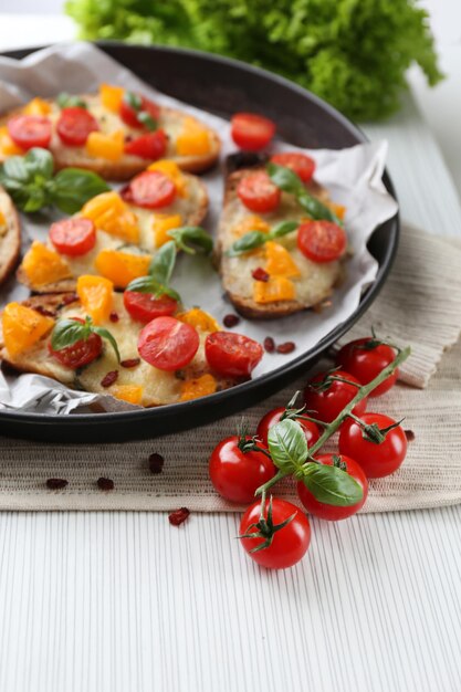 Leckere Bruschetta mit Tomaten in der Pfanne auf dem Tisch