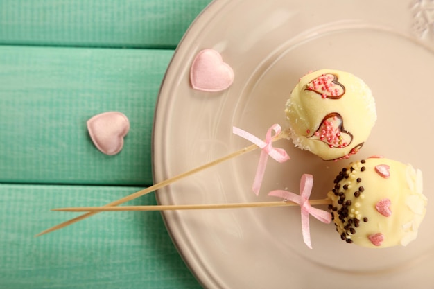 Leckere Cake Pops auf Teller, auf Holztisch