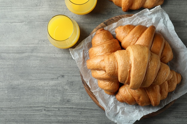 Leckere Croissants und Saft auf grau strukturiertem Tisch