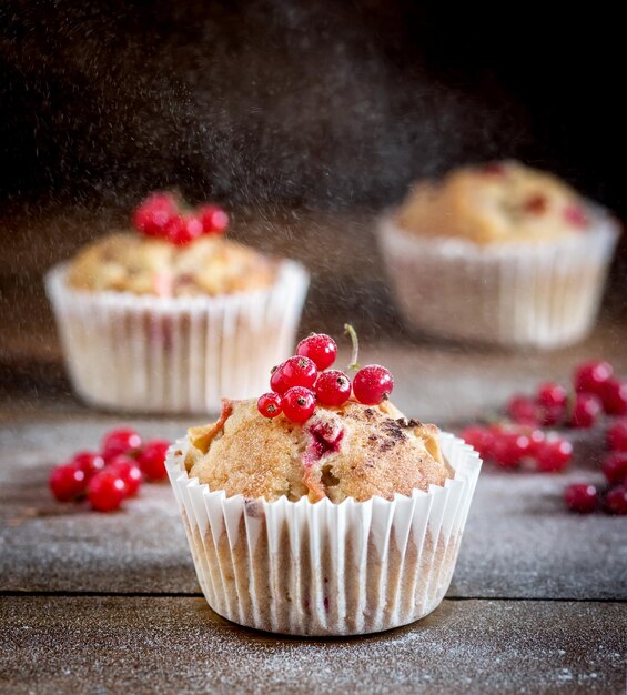 Leckere Cupcakes mit Beeren auf Holzhintergrund Hausgemachter Cupcake mit Beerenapfel und Gewürzen Vertikaler Puderzucker