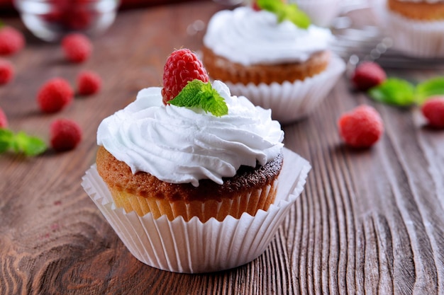 Leckere Cupcakes mit Beeren und frischer Minze auf Holztisch hautnah